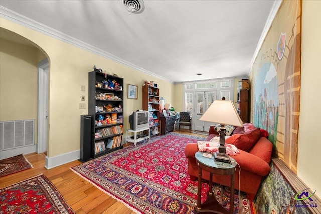 living room featuring french doors, light wood-type flooring, and crown molding