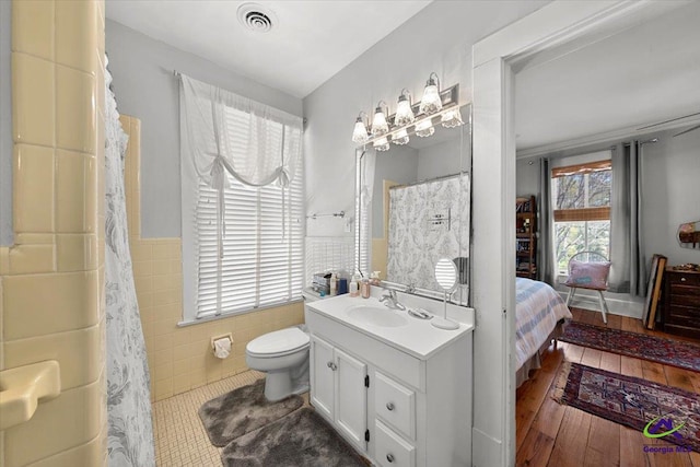 bathroom with tile walls, toilet, wood-type flooring, and vanity with extensive cabinet space