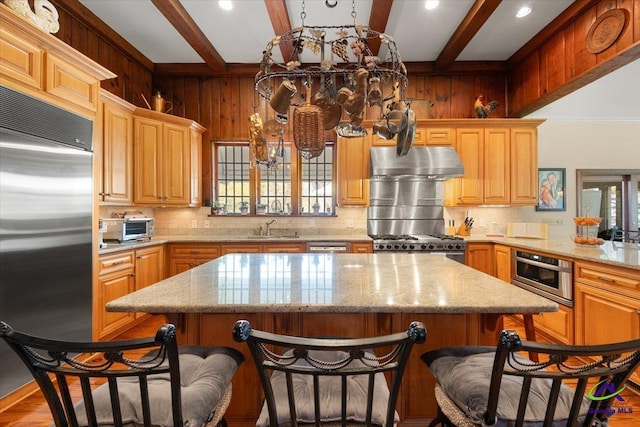 kitchen with a kitchen island, appliances with stainless steel finishes, light stone counters, and hardwood / wood-style floors