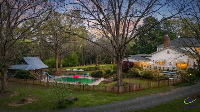 yard at dusk with a fenced in pool