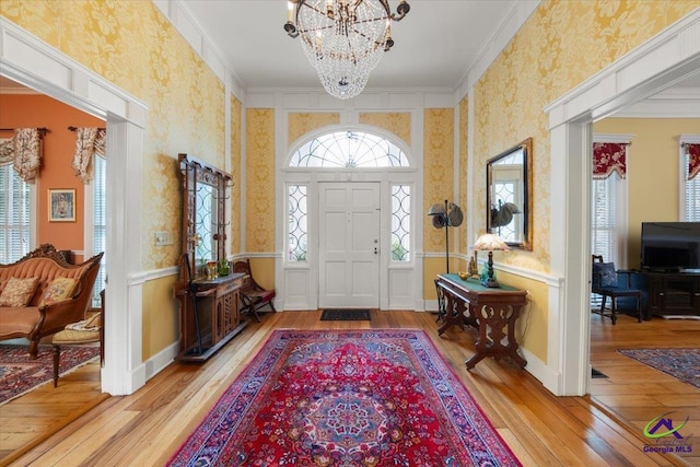 entryway featuring an inviting chandelier, crown molding, and light hardwood / wood-style flooring