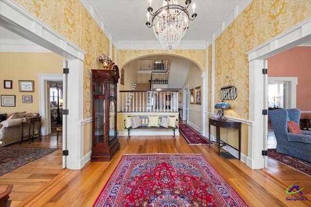 entryway featuring a notable chandelier, ornamental molding, a wealth of natural light, and light hardwood / wood-style floors