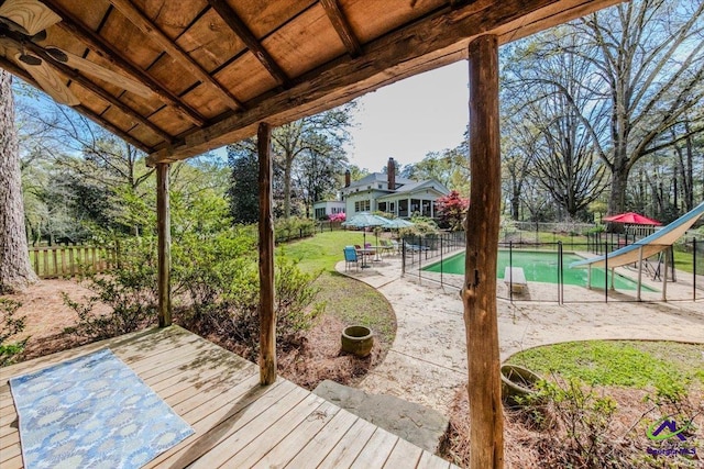 deck featuring a patio, a lawn, and a fenced in pool