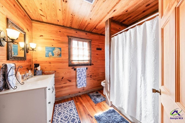 bathroom with wooden walls, hardwood / wood-style floors, large vanity, and toilet