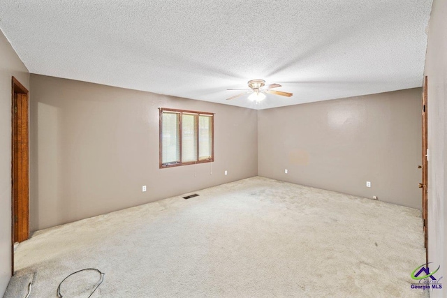 unfurnished room with ceiling fan, a textured ceiling, and light colored carpet