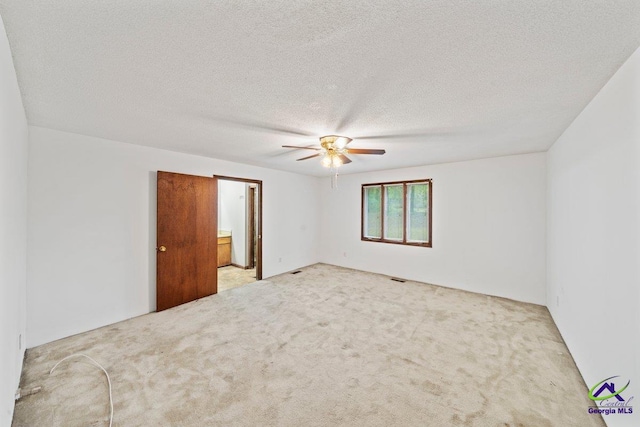 spare room with ceiling fan, light carpet, and a textured ceiling