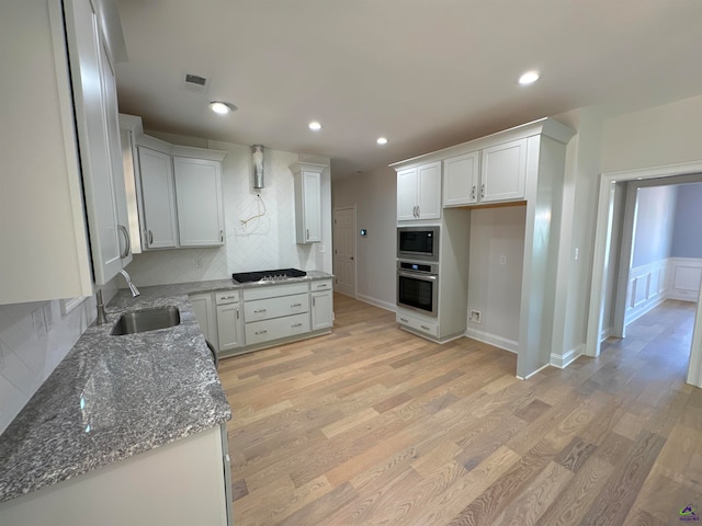 kitchen featuring black gas cooktop, white cabinets, oven, sink, and built in microwave