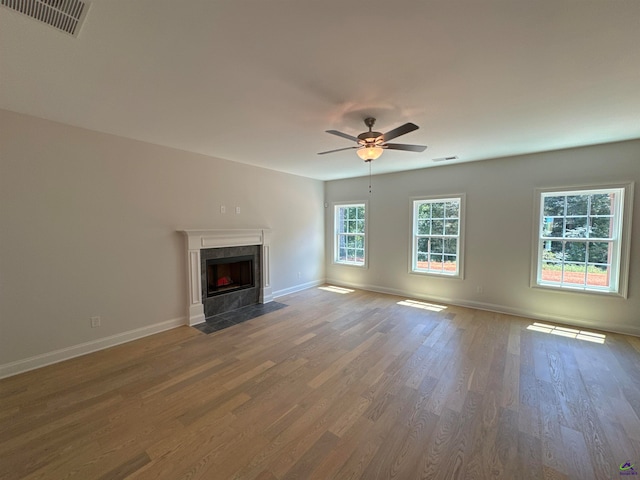 unfurnished living room with a premium fireplace, hardwood / wood-style floors, and ceiling fan