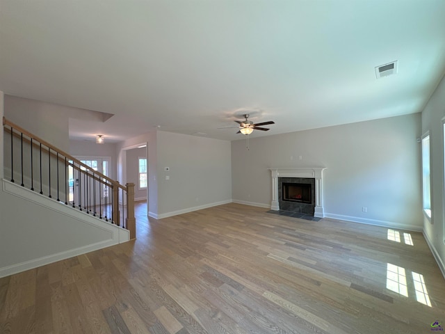 unfurnished living room with light hardwood / wood-style floors, ceiling fan, and a premium fireplace