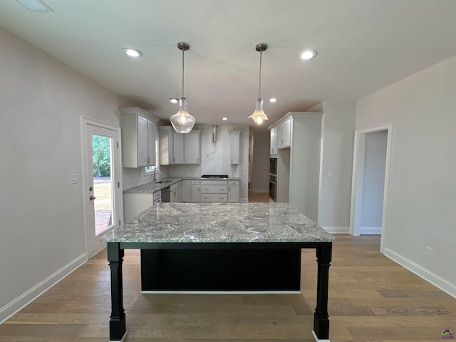 kitchen with pendant lighting, a center island, white cabinetry, and sink