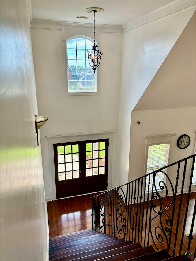 foyer featuring french doors, dark hardwood / wood-style floors, an inviting chandelier, and ornamental molding