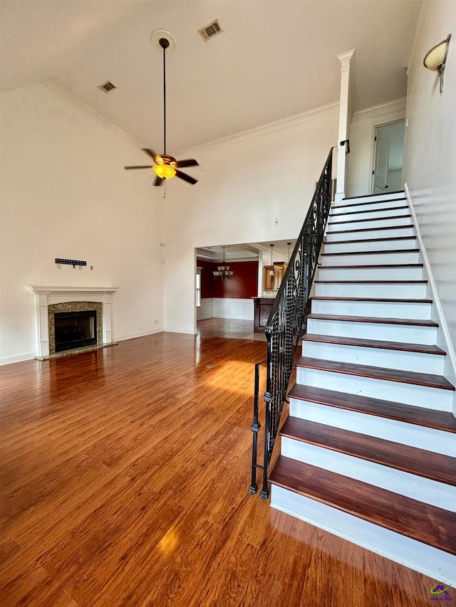 staircase featuring crown molding, ceiling fan with notable chandelier, and hardwood / wood-style flooring