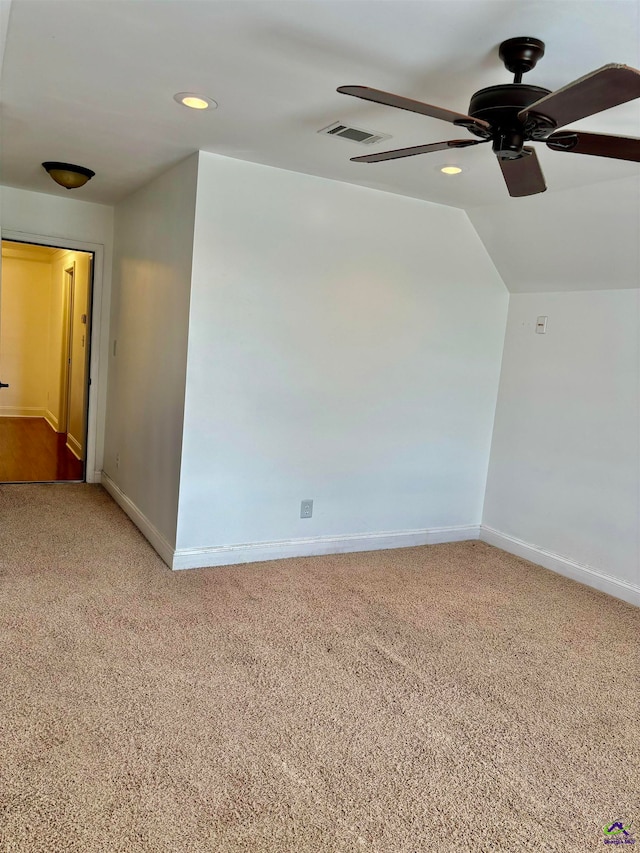 empty room with vaulted ceiling, ceiling fan, and carpet flooring