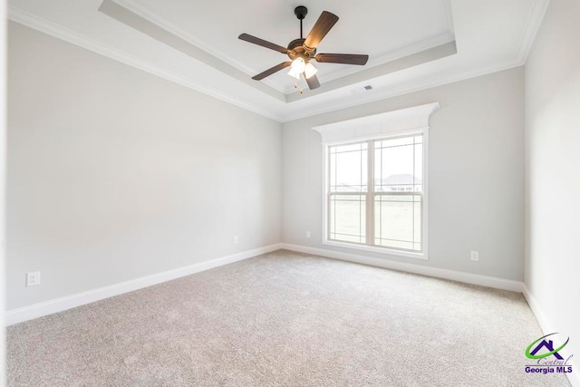 empty room featuring ornamental molding, carpet flooring, ceiling fan, and a raised ceiling