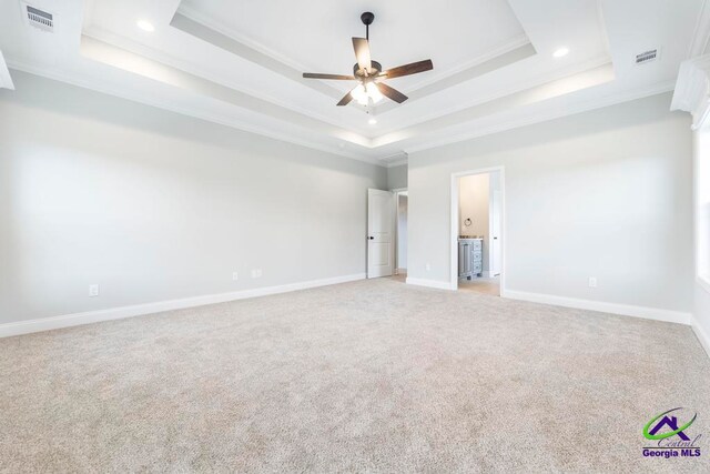 unfurnished bedroom featuring light colored carpet, ceiling fan, crown molding, and a tray ceiling