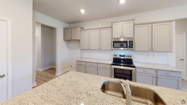 kitchen featuring light hardwood / wood-style floors, sink, light stone countertops, and stainless steel appliances