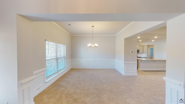 unfurnished room featuring ornamental molding, an inviting chandelier, and light colored carpet