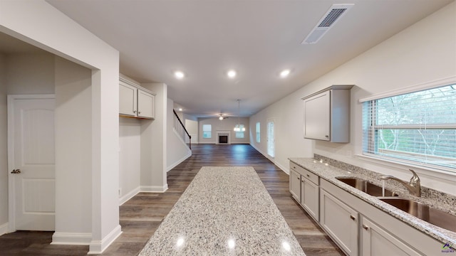 kitchen with light stone countertops, gray cabinetry, and sink