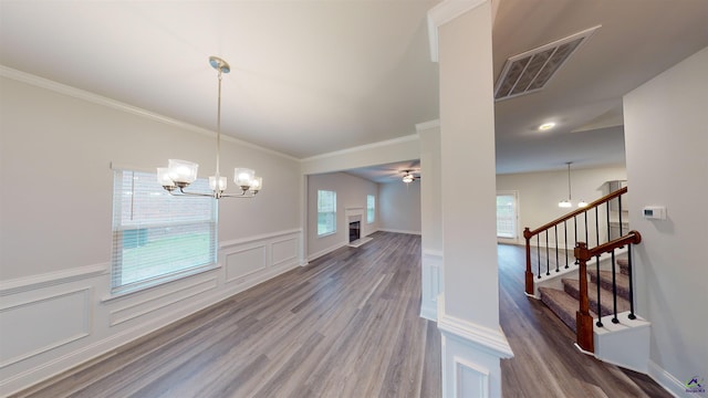 dining room featuring wood-type flooring, a wealth of natural light, crown molding, and ceiling fan with notable chandelier