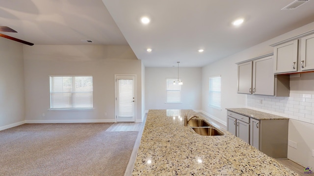 kitchen with pendant lighting, sink, backsplash, gray cabinetry, and light stone counters