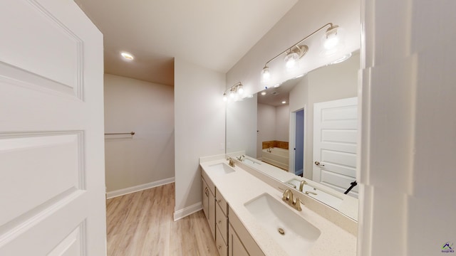 bathroom with hardwood / wood-style flooring, vanity, and a bathtub