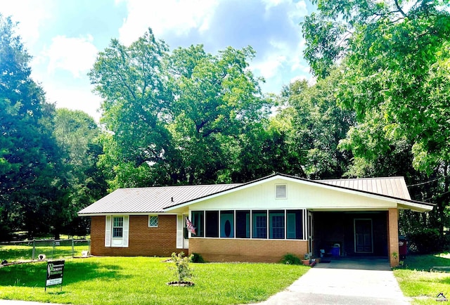 ranch-style home featuring a carport, a sunroom, and a front yard