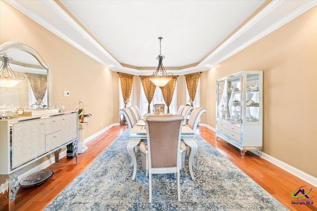 dining area with a tray ceiling, hardwood / wood-style flooring, and ornamental molding