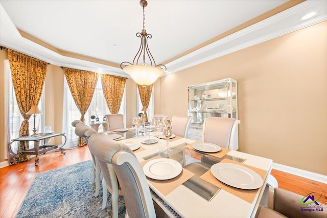 dining room featuring crown molding, a raised ceiling, and hardwood / wood-style floors