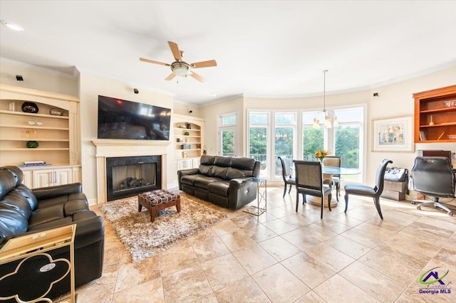 tiled living room featuring built in shelves, ornamental molding, and ceiling fan with notable chandelier