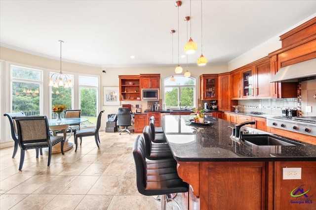 kitchen with appliances with stainless steel finishes, dark stone counters, a notable chandelier, sink, and light tile floors