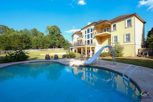 back of house with a patio, a lawn, a balcony, and a fenced in pool