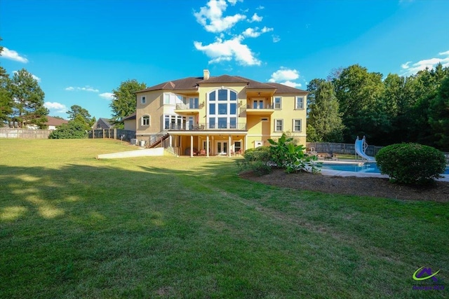 back of property featuring a balcony and a lawn