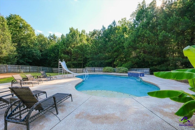 view of swimming pool featuring a water slide and a patio