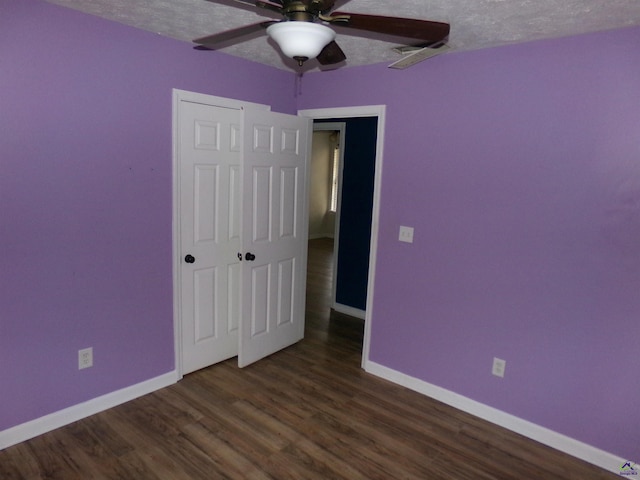 unfurnished bedroom with a textured ceiling, wood finished floors, a ceiling fan, and baseboards