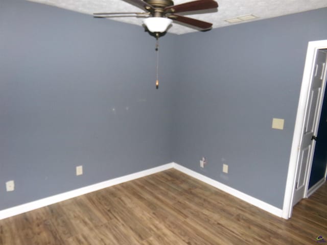 empty room featuring dark wood-style floors, visible vents, ceiling fan, and baseboards