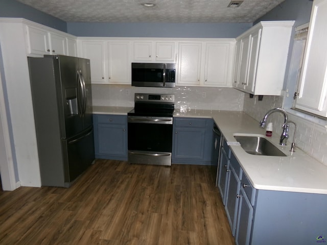 kitchen with white cabinets, appliances with stainless steel finishes, dark wood finished floors, and a sink