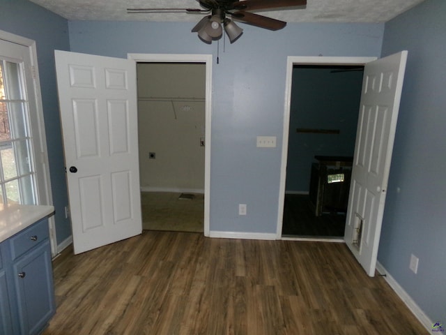 unfurnished bedroom featuring dark wood-style floors, multiple windows, and a walk in closet