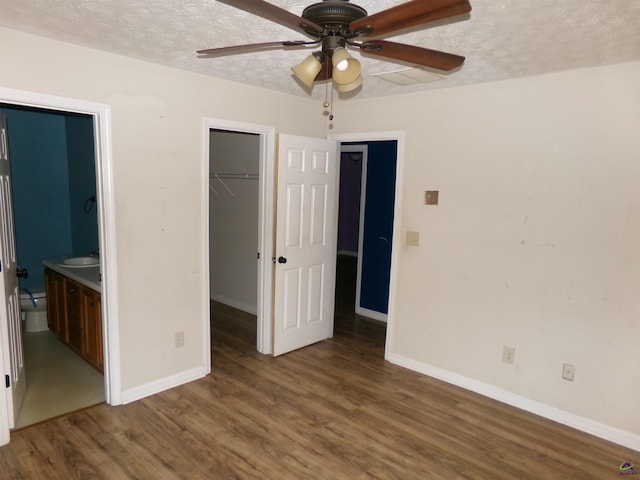 unfurnished bedroom featuring a closet, a sink, a textured ceiling, and wood finished floors