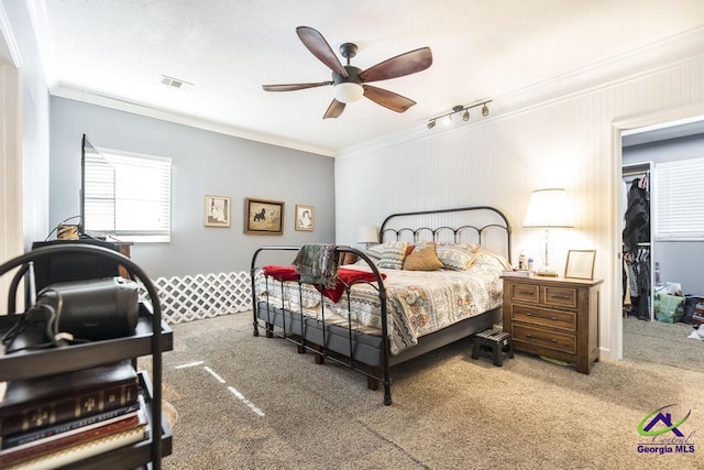 bedroom featuring ceiling fan, carpet flooring, track lighting, ornamental molding, and a closet