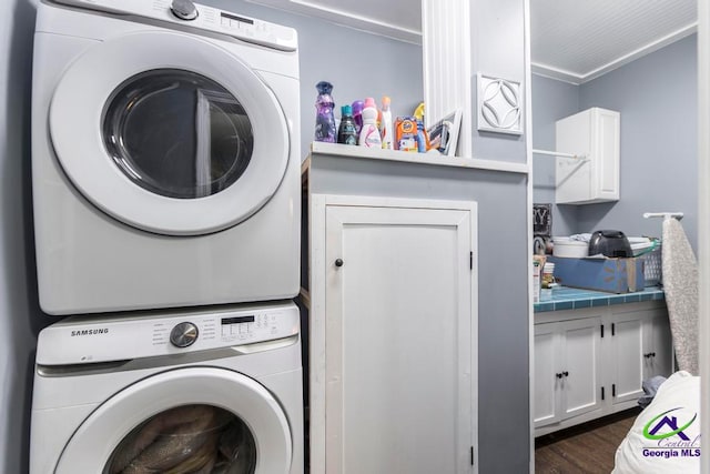 washroom featuring dark wood-type flooring, ornamental molding, and stacked washer and clothes dryer