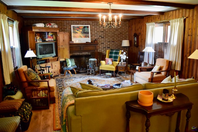 living room featuring beam ceiling, a notable chandelier, wood walls, hardwood / wood-style flooring, and a fireplace