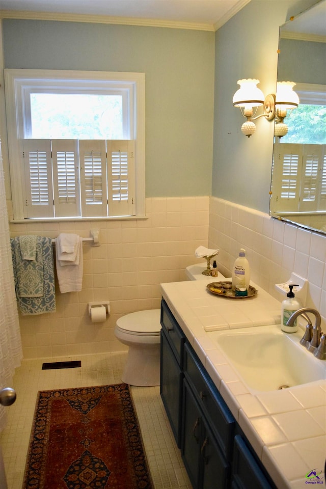 bathroom featuring toilet, tile patterned floors, a healthy amount of sunlight, and tile walls