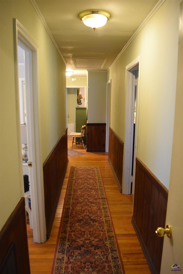 corridor with light wood-type flooring and ornamental molding