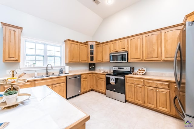 kitchen featuring light tile patterned floors, vaulted ceiling, sink, and stainless steel appliances