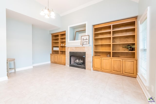 unfurnished living room with built in shelves, a tile fireplace, and a chandelier