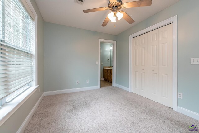 unfurnished bedroom featuring ceiling fan, connected bathroom, a closet, and light carpet