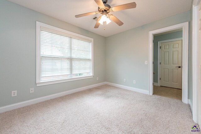 carpeted spare room with ceiling fan