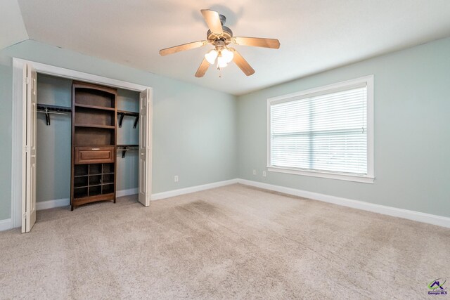 unfurnished bedroom featuring ceiling fan, a closet, and light carpet