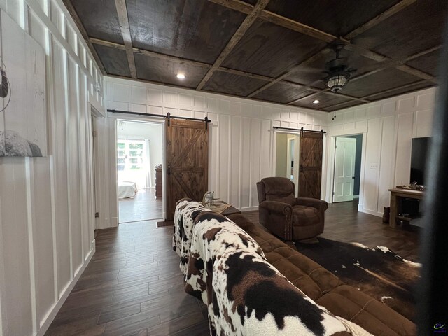 living room with dark wood-type flooring, coffered ceiling, and a barn door