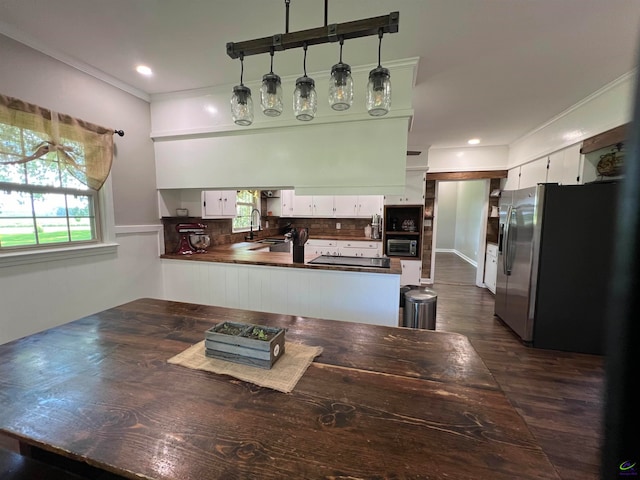 kitchen with white cabinetry, stainless steel refrigerator with ice dispenser, kitchen peninsula, and backsplash